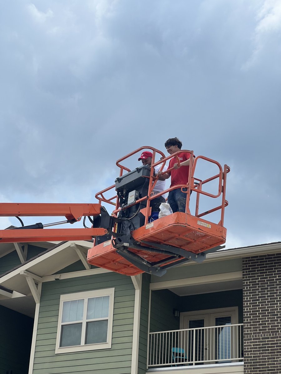 I & G's crew painting apartment exterior from a boom lift